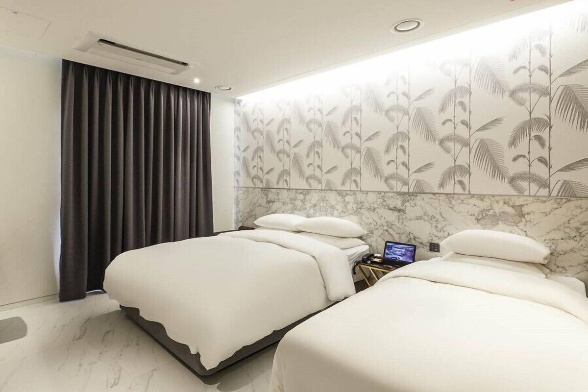 A modern hotel room with a large bed, a desk, and a laptop.