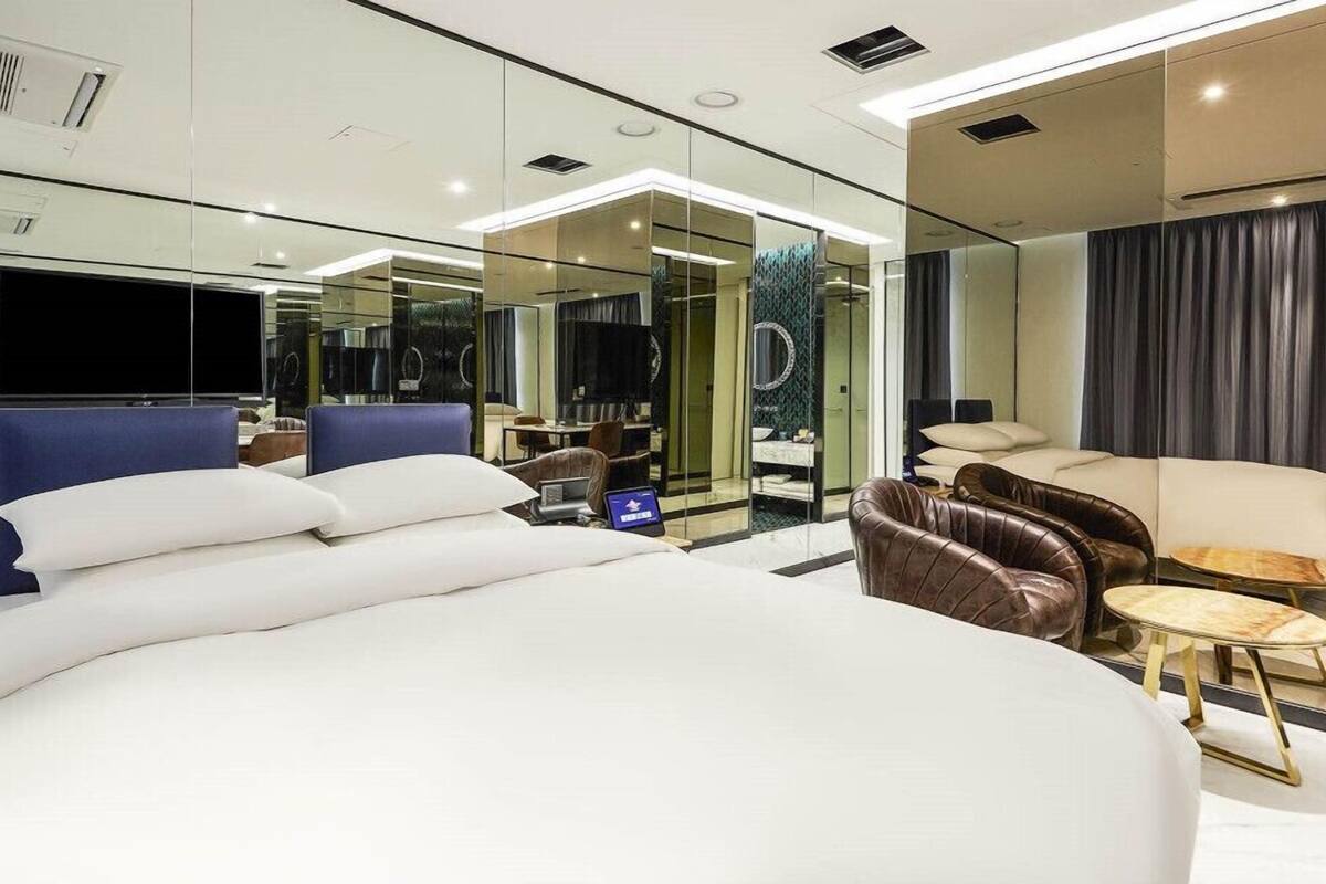 A modern hotel room with a large bed, a seating area with a sofa and armchairs, a small table, and a television.