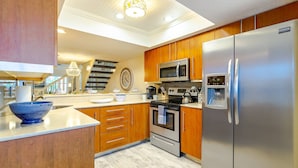 A modern kitchen with wooden cabinets, stainless steel appliances, a built-in oven, microwave, and refrigerator. - Siesta Bayside 3BR Villa: Rare, Spacious Layout, Pickleball, Heated Pools, & Private Beach Access (Siesta Key)