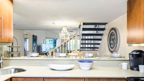 A modern kitchen with wooden cabinets, a stainless steel sink, and a coffee maker. - Siesta Bayside 3BR Villa: Rare, Spacious Layout, Pickleball, Heated Pools, & Private Beach Access (Siesta Key)