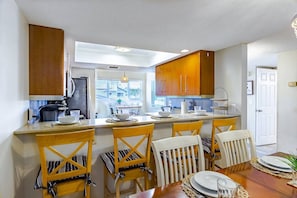 A modern kitchen with wooden cabinets, a central island with seating, and a view to the outside. - Spacious Siesta Bayside 3BR: Private Beach & Lanai (Siesta Key)