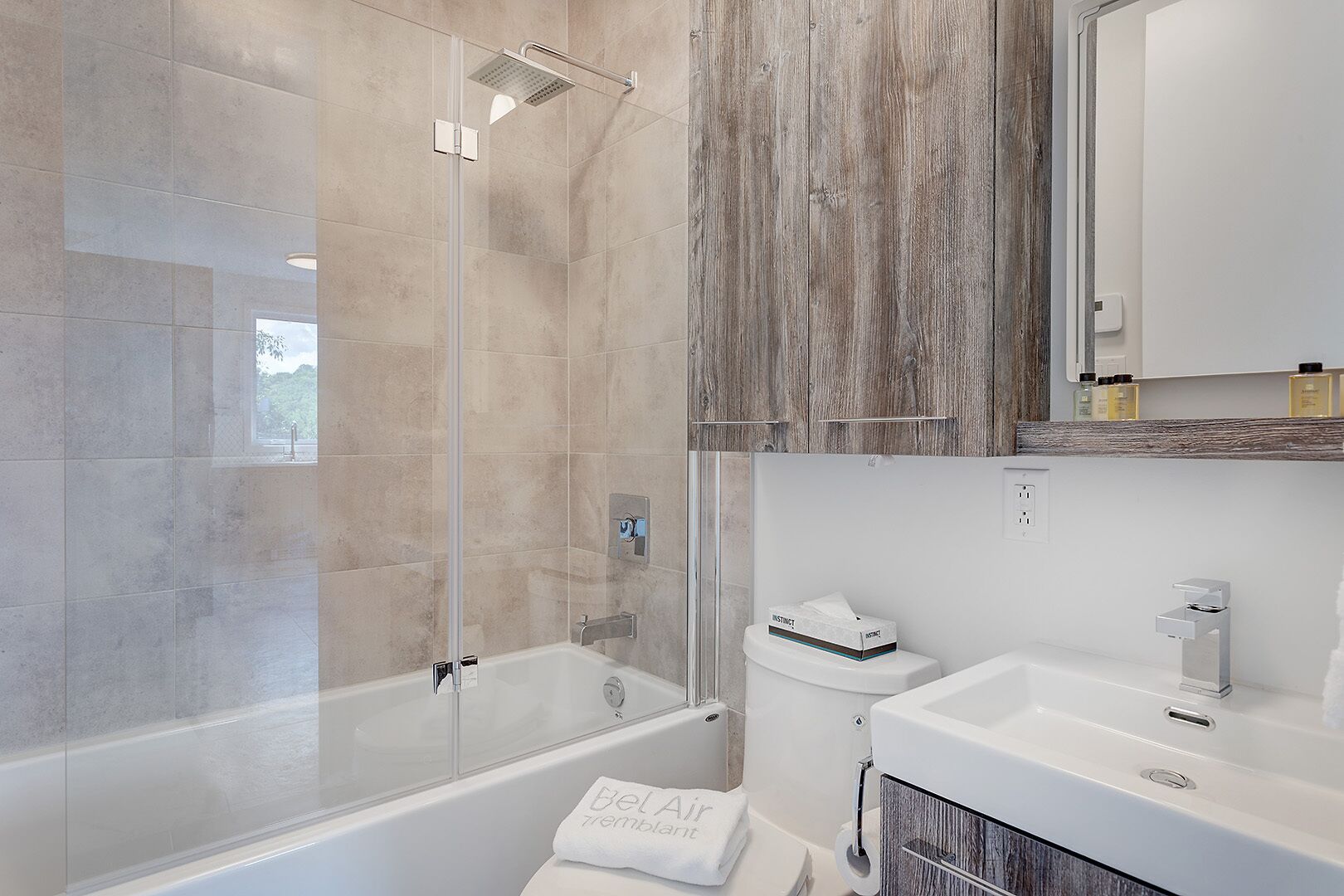 A modern bathroom with a glass-enclosed shower, a bathtub, and a vanity with a mirror.