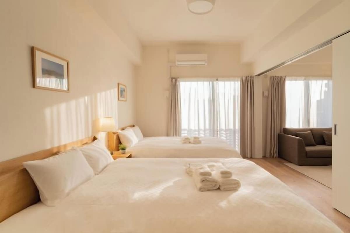 A hotel room with two beds, a sofa, and a view of the city.