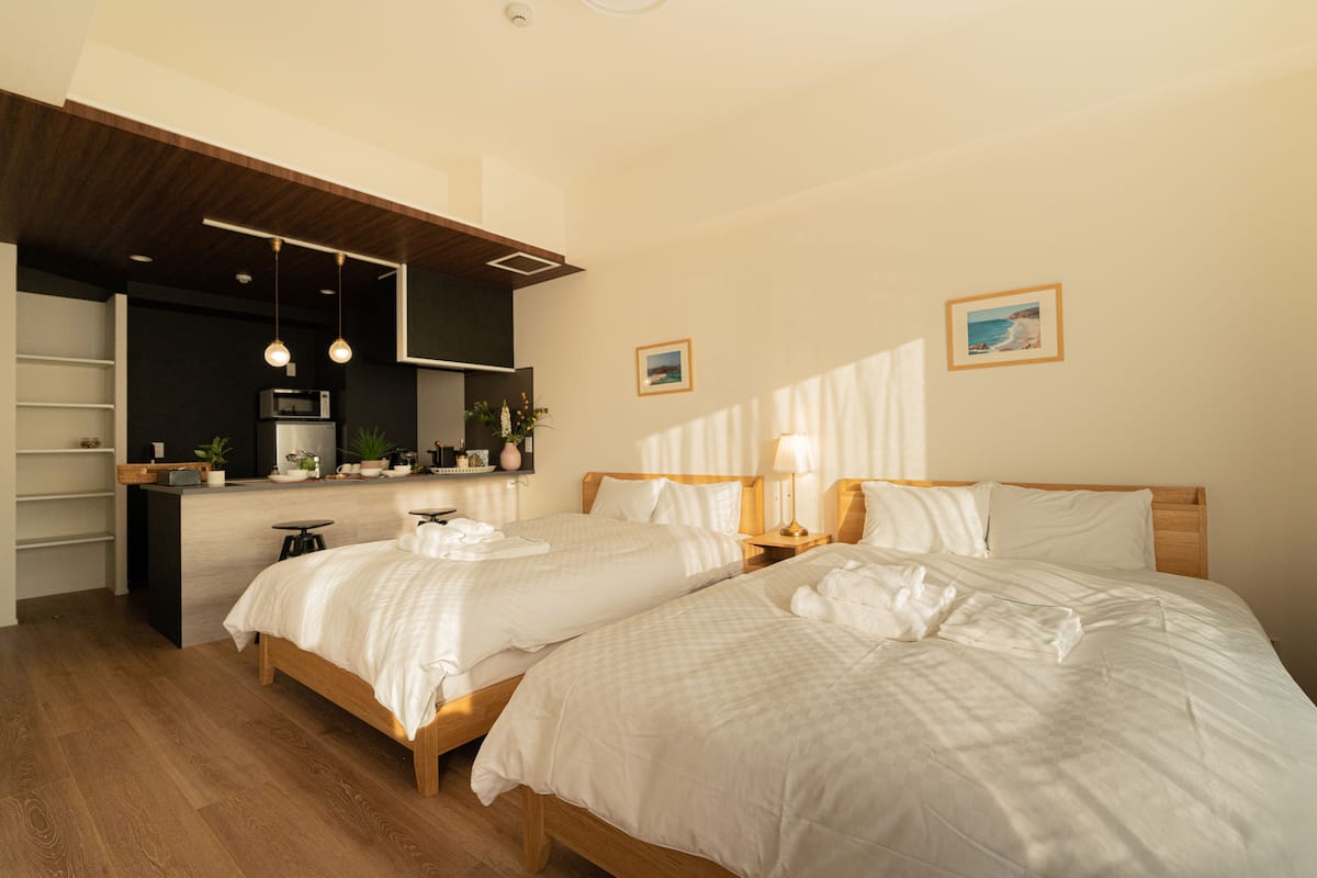 A hotel room with two beds, a kitchenette, and a wooden ceiling.