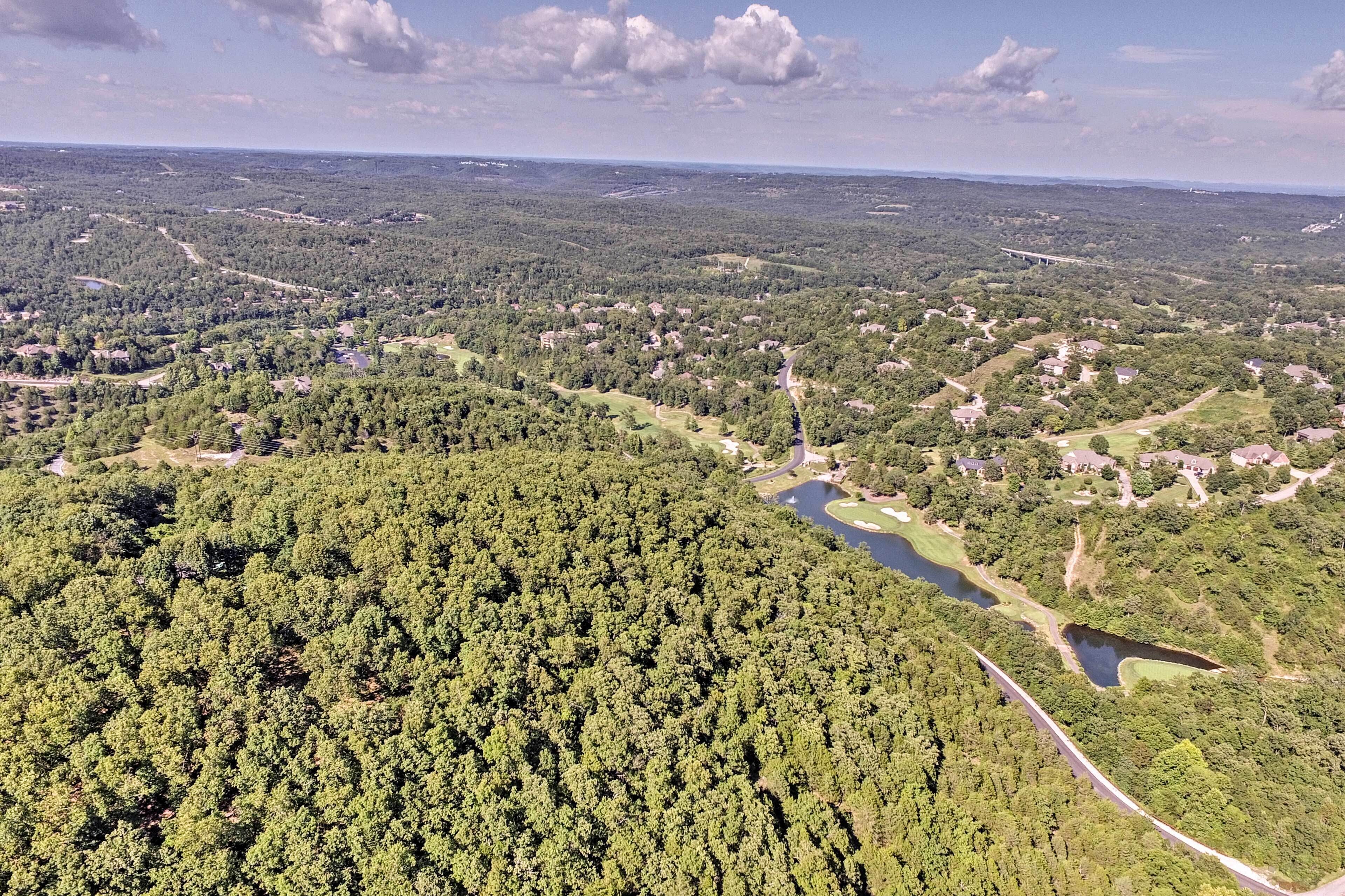 An aerial view of a forested area with a river, roads, and scattered buildings.