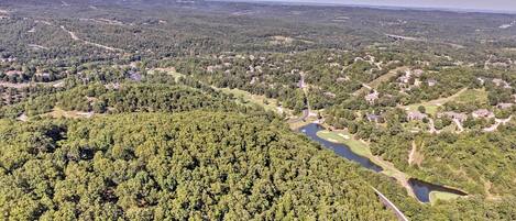 An aerial view of a forested area with a river, roads, and scattered buildings.