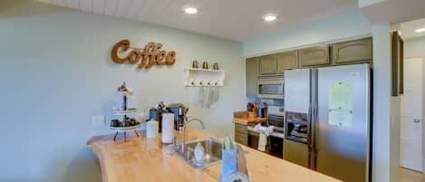 Una cocina con encimera de madera, electrodomésticos de acero inoxidable y un letrero de café en la pared.