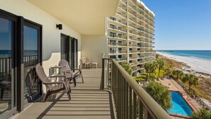 Un balcon avec coin salon extérieur, une piscine et une vue sur la plage et l’océan.