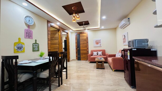 A modern living room with a dining area, a sofa set, a kitchen area with a microwave, and a ceiling fan.