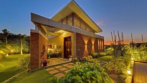 Une maison moderne avec une façade en briques, une grande véranda et un jardin bien entretenu.