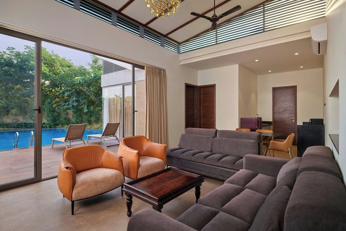 A spacious living room with a large sofa set, a coffee table, and a view of a swimming pool.