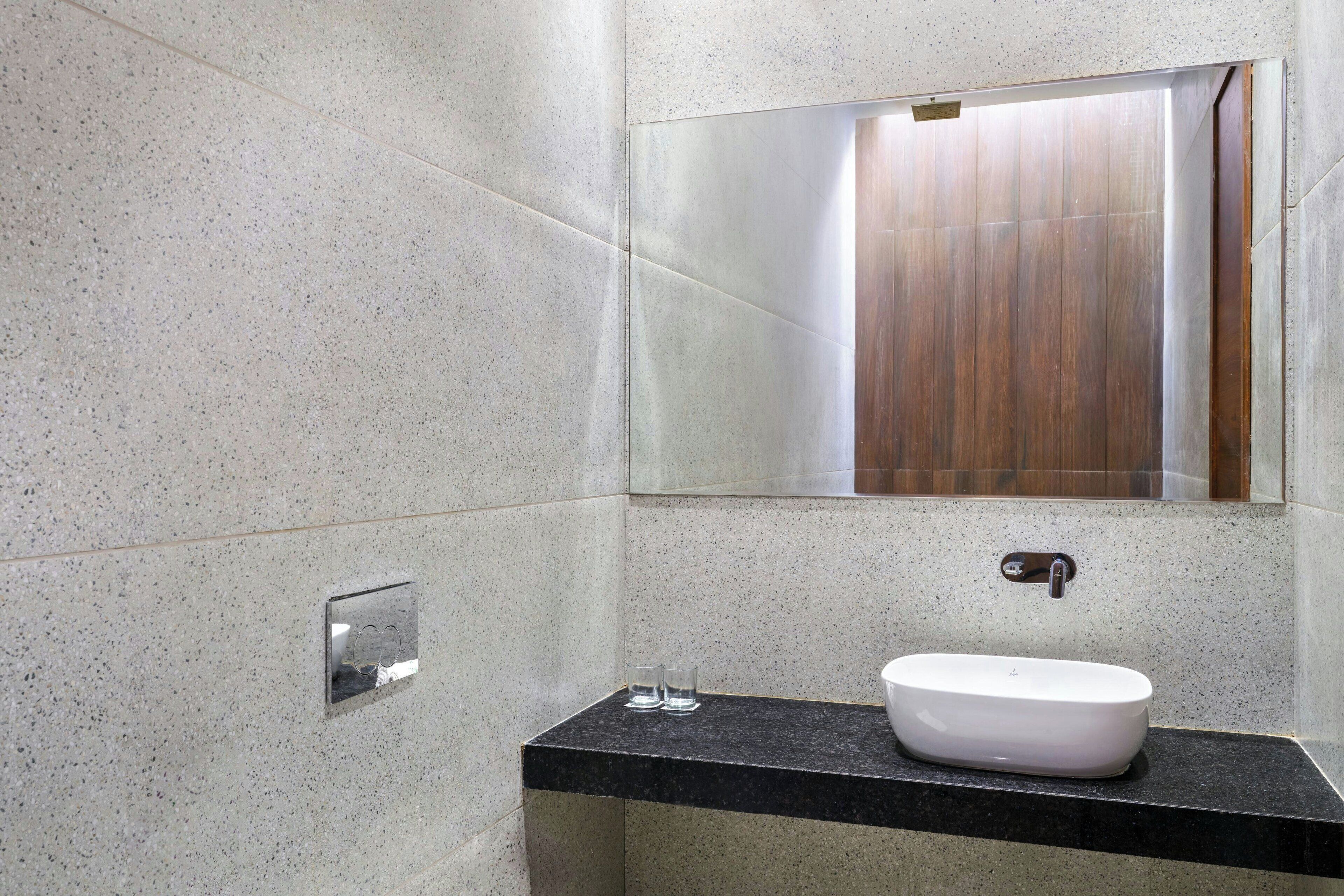 Un bagno moderno con un lavandino a colonna, uno specchio e un box doccia.