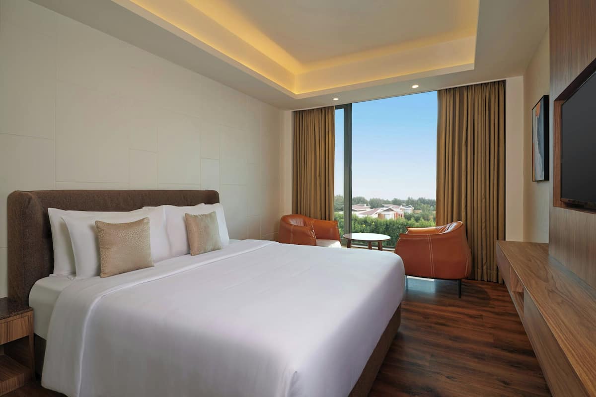 A hotel room with a large bed, a seating area with a table, and a TV.
