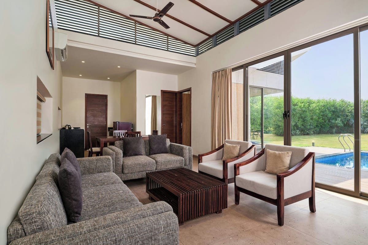 A spacious living area with a high ceiling, a ceiling fan, and a large sliding glass door leading to a pool.