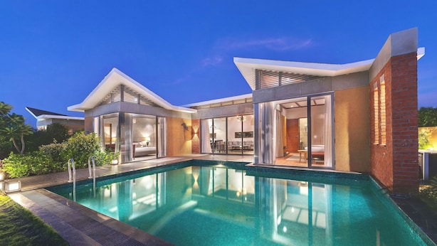 Une maison moderne dotée d’une piscine, de grandes portes vitrées et d’une façade en briques.