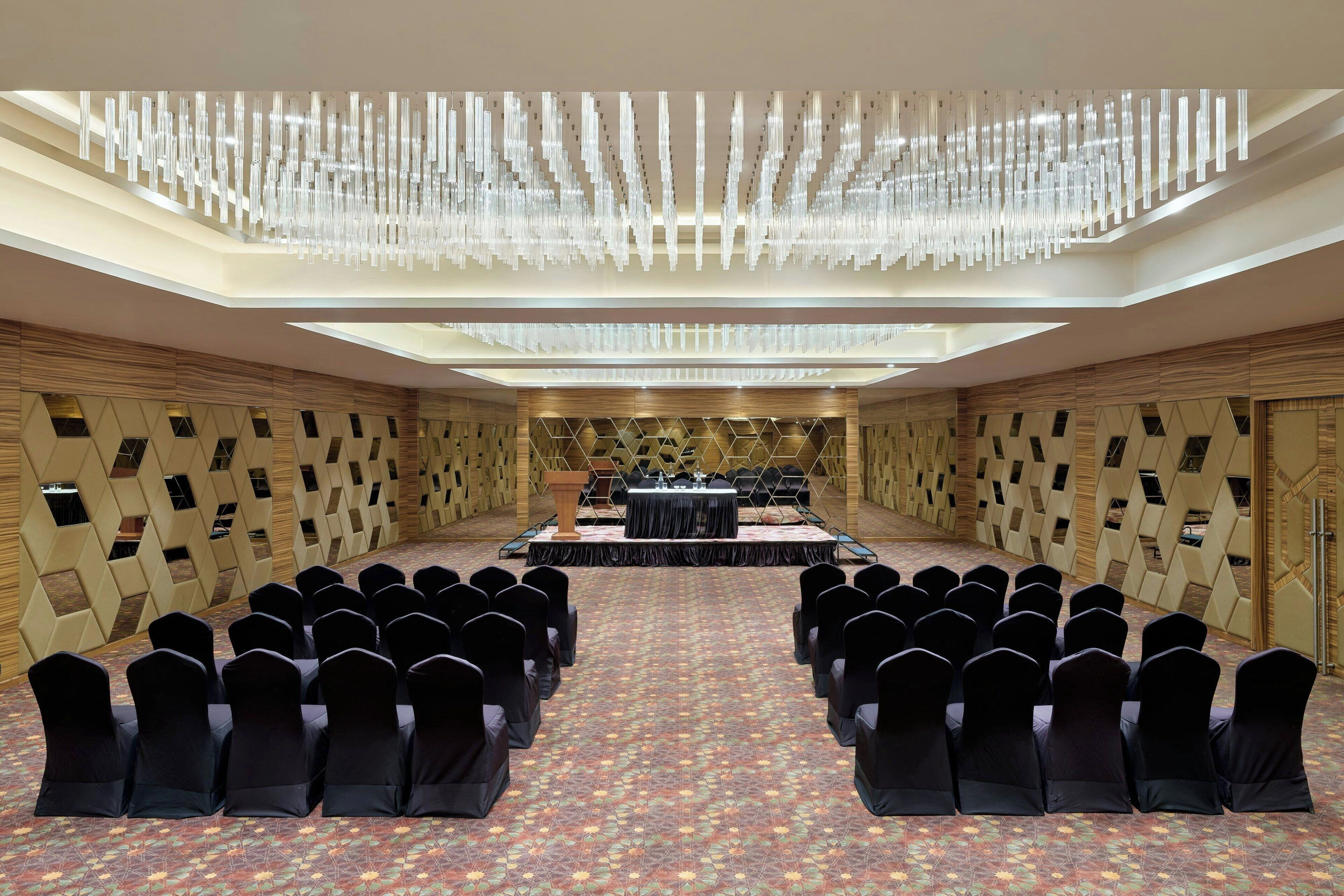 A conference room with a stage, rows of chairs, and a patterned carpet.