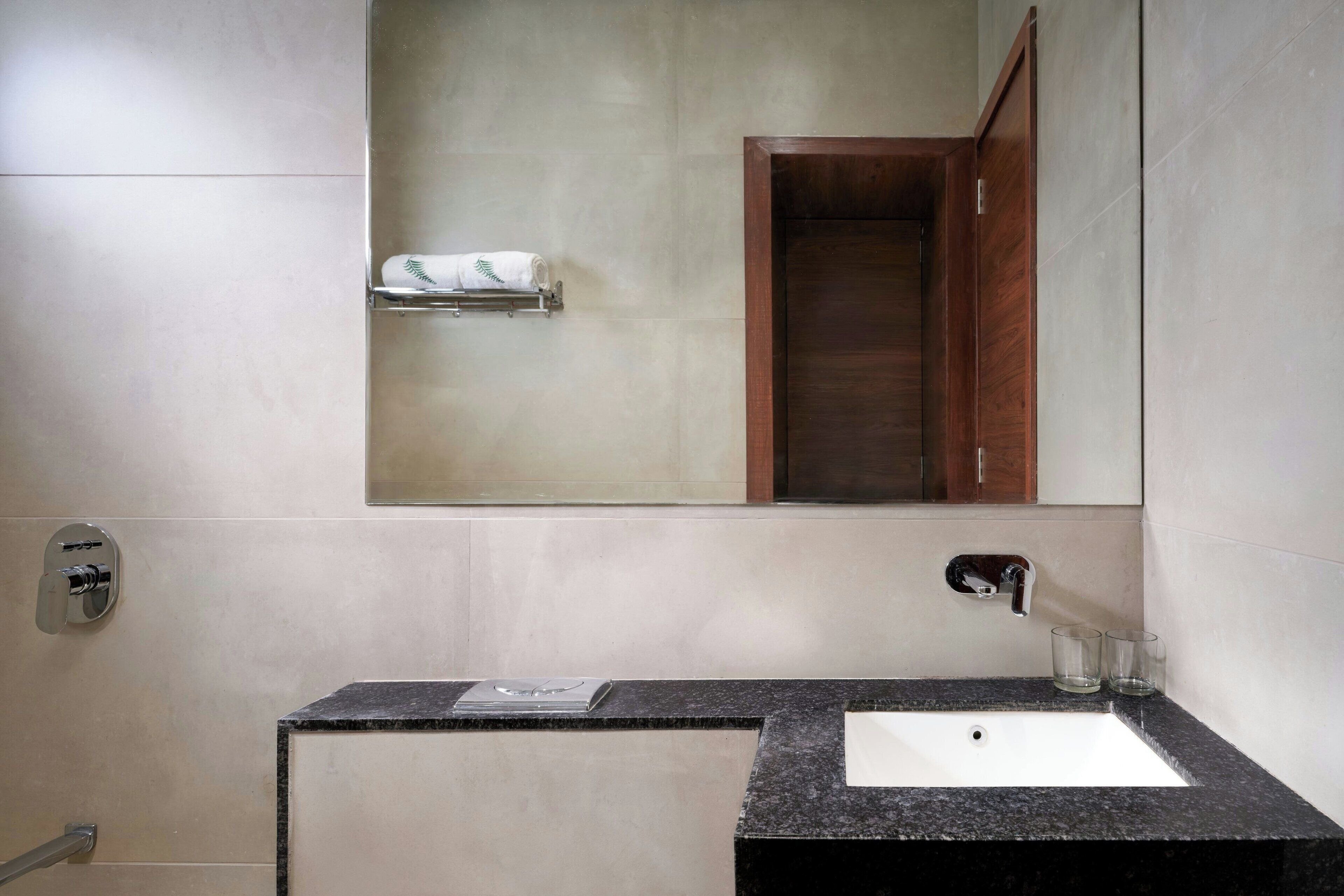 A bathroom with a white sink, a mirror, a towel rack, and a wooden cabinet.