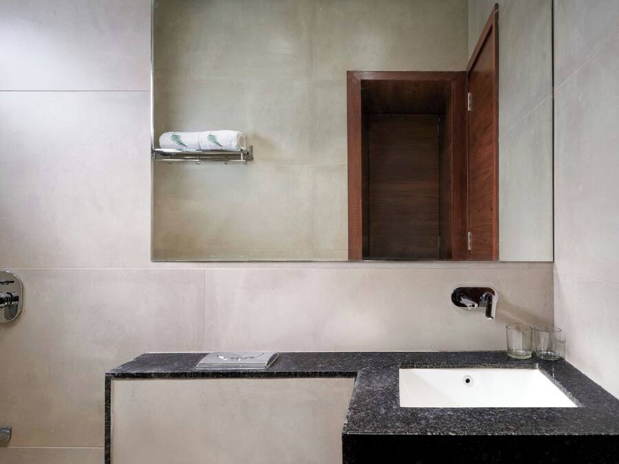 A bathroom with a white sink, a mirror, a towel rack, and a wooden cabinet.