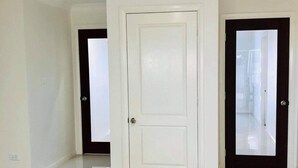 A spacious, empty room with a large white door in the center, flanked by two smaller doors with frosted glass panels. - Large 6 bed home, walk to water, restaurants, pub, club, coffee, use of kayaks. (Salamander Bay)