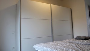 Une chambre à coucher avec un lit, une armoire et une table de chevet.