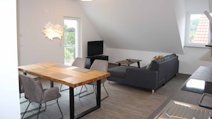 Un espace de vie moderne comprenant un coin repas, un canapé, un téléviseur et un coin cuisine.