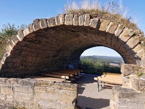 Um arco de pedra com bancos no interior, com vista para uma paisagem deslumbrante.