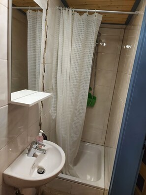 A bathroom with a white sink, a mirror, and a shower with a white curtain.