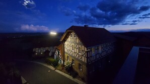 A traditional half-timbered house with a sloped roof, a visible chimney, and a street lamp nearby. - Ferienwohnung Altenstein (Maroldsweisach)