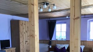 A wooden cabin-style room with a bed, a desk, and a television. - Ferienwohnung Altenstein (Maroldsweisach)