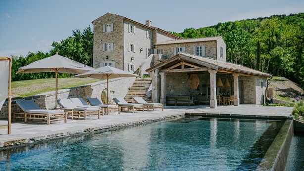 A stone building with a pool, lounge chairs, and umbrellas. - Luxury estate with 60.000 sqm land near hilltop town Motovun (Motovun)