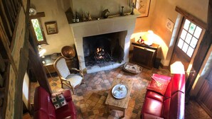 Un salon chaleureux avec une cheminée, des canapés en cuir rouge et un sol carrelé.