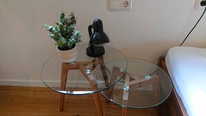 A small glass table with a potted plant and a lamp on a wooden stand. - Gemütliche Ferienwohnung am Ortsrand (Kreuzwertheim)