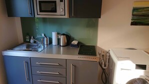 A compact kitchen with a microwave, kettle, kettle, and a small oven. - Gemütliche Ferienwohnung am Ortsrand (Kreuzwertheim)