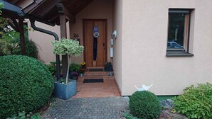 A house entrance with a wooden door, number 26, potted plants, and a small window. - Gemütliche Ferienwohnung am Ortsrand (Kreuzwertheim)