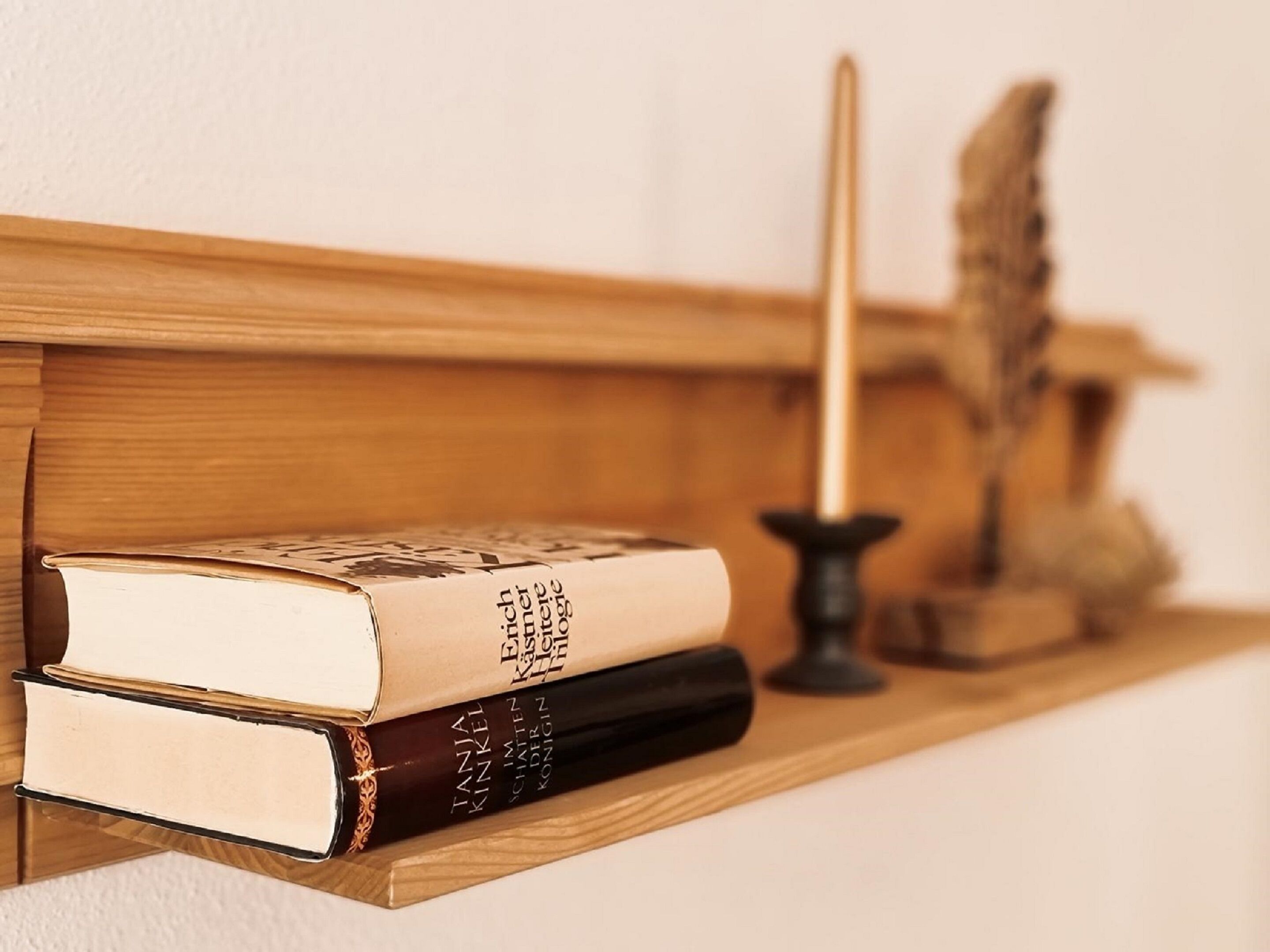 Una estantería de madera con dos libros y un candelabro.