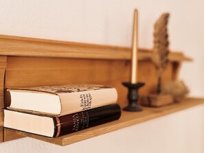 Une étagère en bois avec deux livres et un chandelier.