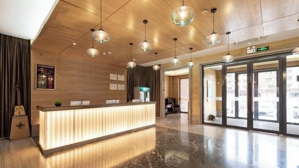 A modern hotel lobby with a reception desk, pendant lighting, and a view of the outside through large glass doors. - Jinyi Hotel (Runyu store of Hohhot University of Technology) (Hohhot)