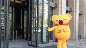 A large bear mascot outside a building with glass doors and a doormat with Chinese characters. - Jinyi Hotel (Runyu store of Hohhot University of Technology) (Hohhot)