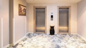 A hallway with two elevators, a painting on the wall, and a trash bin. - Jinyi Hotel (Runyu store of Hohhot University of Technology) (Hohhot)