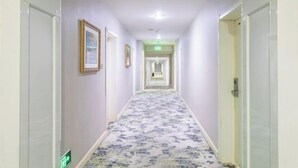 A narrow hallway with patterned flooring, framed pictures on the walls, and doors on both sides. - Jinyi Hotel (Runyu store of Hohhot University of Technology) (Hohhot)