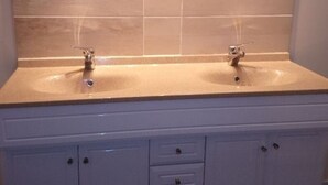 A bathroom with two sinks, a mirror, and a cabinet with drawers.
