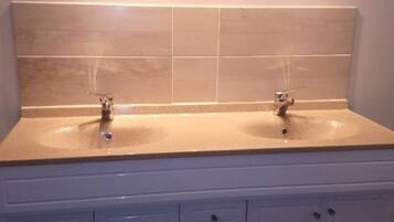 A bathroom with two sinks, a mirror, and a cabinet with drawers.