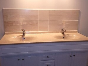A bathroom with two sinks, a mirror, and a cabinet with drawers.