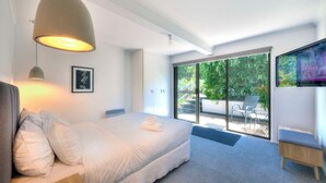 A modern bedroom with a large bed, a desk, and a TV.