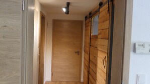 Un pasillo con paredes y piso de madera, que conduce a una puerta al final.