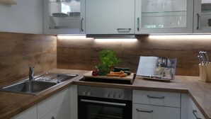 Una cocina moderna con un lavamanos de acero inoxidable, encimera de madera y armarios empotrados.