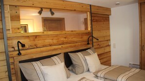 Una habitación con paneles de madera, una cama, dos mesitas de noche y un espejo.