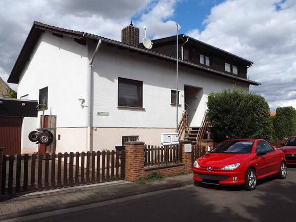 A two-story house with a white exterior, a brick chimney, and a satellite dish. - Ferienwohnung Olm (Dolgesheim)