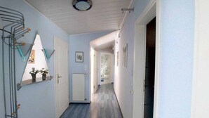Kapea käytävä, jossa on puulattia, valkoiset seinät ja kattovalaisin.