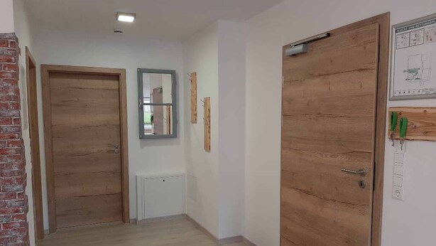 A hallway with wooden doors, a radiator, and a mirror on the wall.
